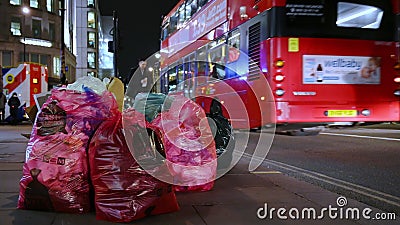 Trash bags stacked on sidewalk along The Strand, London at night. LONDON - FEBRUARY 03, 2020: Trash bags stacked on sidewalk along The Strand, London at night as Trash bags stacked on sidewalk along The Strand, London at night. LONDON - FEBRUARY 03, 2020: Trash bags stacked on sidewalk along The Strand, London at night as