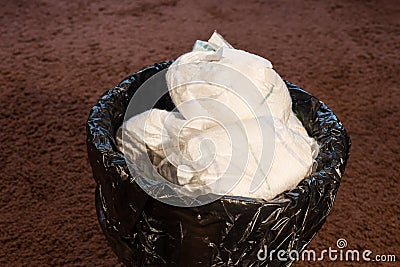 A trash bin full of dirty used baby`s diapers. Disposable nappies Stock Photo