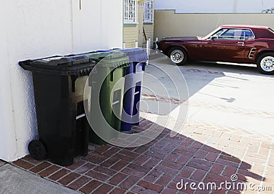 Trash bins for separate garbage disposal, outside the house at the entrance to the garage and a parked red car with the style of t Stock Photo