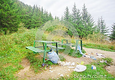 Trash and garbage near bench in mountain forest landscape Stock Photo