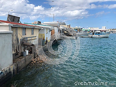 Trash and garbage in water behind run down dilapidated houses Stock Photo