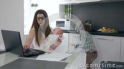 Travail de maman d'affaires sur l'ordinateur portable et essai de calmer le fils pleurant de bébé sur la cuisine clips vidéos Travail de maman d'affaires sur l'ordinateur portable et essai de calmer le fils pleurant de bébé sur la cuisine clips vidéos