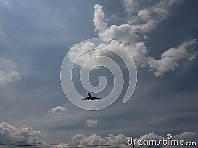 blue sky with white clouds and the silhouette of a plane Stock Photo