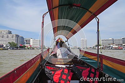 Travel along the Chao Phraya River on a long tourist boat. The driver is sitting in front and talking on phone Editorial Stock Photo