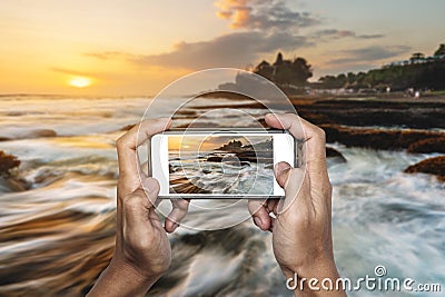 Travel Asia, hand taking photo of Tanah Lot temple in Bali, by mobile smart phone Stock Photo