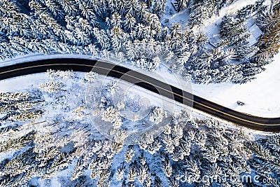 Travel background. Black road in white forest covered with snow. Aerial drone view. Stock Photo