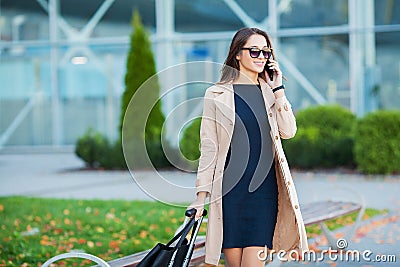 Travel. Business Woman in airport talking on the smartphone while walking with hand luggage in airport going to gate Stock Photo
