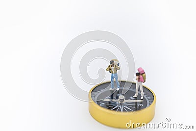 Travel Concept. Close up of two traveler miniature figure with backpack standing on compass on white background and copy space Stock Photo