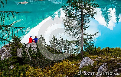 Travel concept. The couple sitting on the shore of famous lake Sorapis with turquoise water. Very popular location for photography Stock Photo