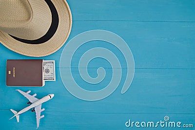 Travel Concept : Flat lay of straw hat, passport with money, plane model, on blue wooden background, with copy space. Stock Photo