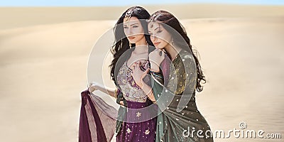 Travel concept. Two gordeous women sisters traveling in desert. Arabian Indian movie stars. Stock Photo