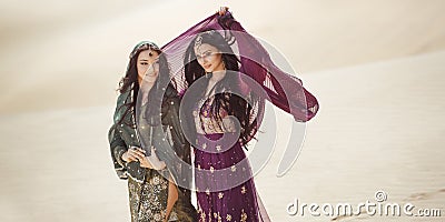 Travel concept. Two gordeous women sisters traveling in desert. Arabian Indian movie stars. Stock Photo