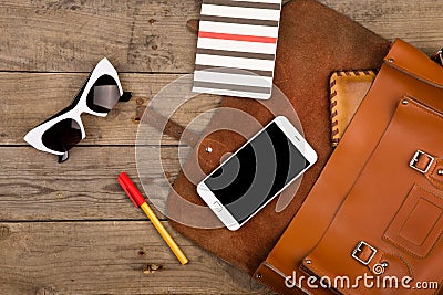 women set with bag, smart phone, sunglasses, notepad, pen and purse on brown wooden desk Stock Photo