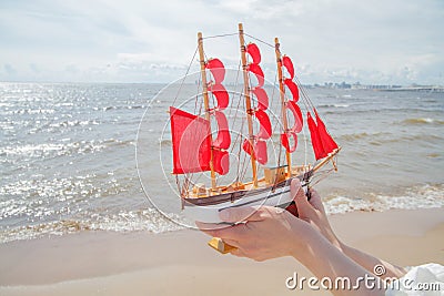 Travel and cruise concept. Ship with red sails against sea, beach and sky clouds Stock Photo
