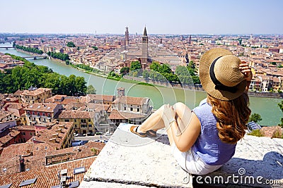 Travel destination Italy. Wide angle from belvedere of young woman sitting on wall enjoying stunning view of Verona, Italy Stock Photo