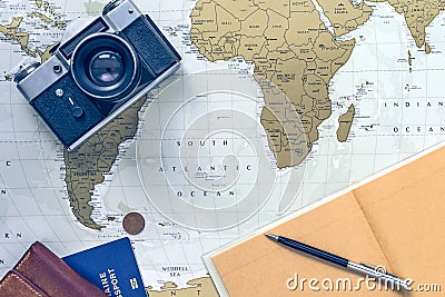 Travel flatlay with wallet, pocketbook, passport, pen and camera on world map Stock Photo