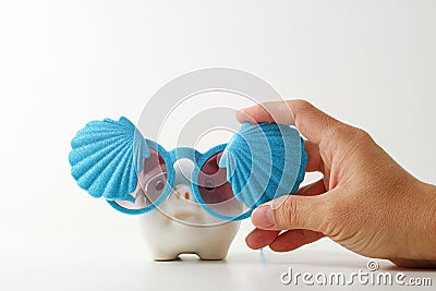 Travel insurance concept.business insurance agent hand in gesture of protection of piggy bank with shell sunglasses on white back Stock Photo