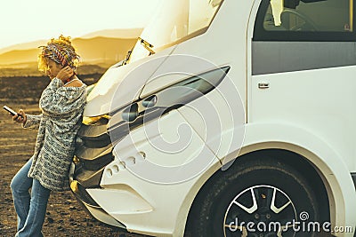 Travel people lifestyle van life with modern camper van. Adult young woman enjoy freedom against a motor home vehicle using mobile Stock Photo