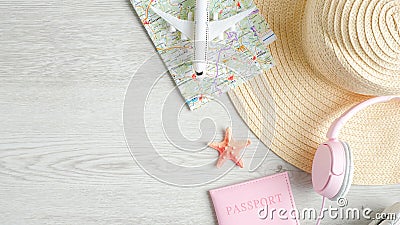 Travel or summer vacation concept on wooden table. Top view airplane model, map, beach hat, pink headphones and passport document Stock Photo