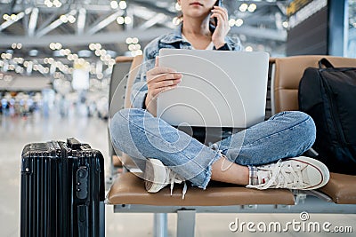 Travel vacation concept, asian female woman uses a smartphone and is working on a laptop, she sit wating for flight schedule at Stock Photo