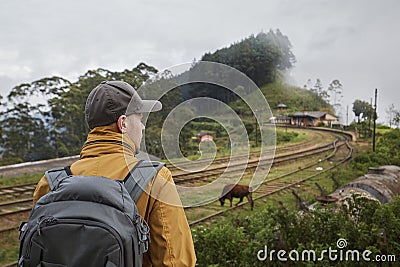 Traveler with backpack looking at rural railroad station Stock Photo