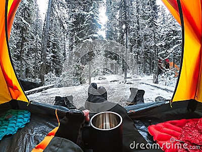 Traveler camping with hand holding cup in a tent with snow in pine forest at national park Stock Photo