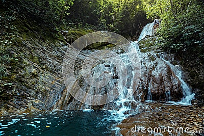 Traveler Explorer Enjoys View Of Waterfall In Deep Forest In Summer, Rear View Stock Photo