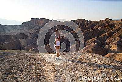 Traveler girl with fit body is standing in white short shorts in front of dry hot lifeless desert landscape, Zabriskie Point USA Stock Photo