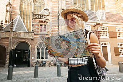 Traveler girl hold and look map in Amsterdam. Hipster tourist searching right direction on map, lifestyle concept adventure Stock Photo