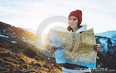 Traveler girl look and hold in hands map, people planning trip, hipster tourist on background sun flare nature, enjoy journey Stock Photo