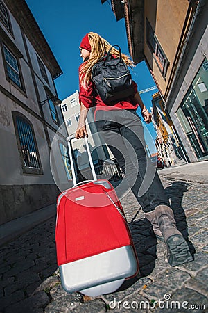 Traveler girl walking in city with red suitcase. Summer. Stock Photo