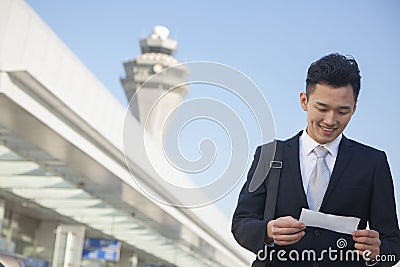 Traveler looking at ticket at airport Stock Photo
