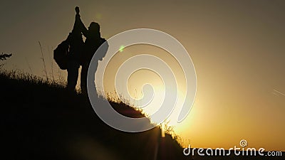 Traveler man extends his hand to a girl climbing to the top of a hill. travelers climb the cliff holding hand. teamwork Stock Photo