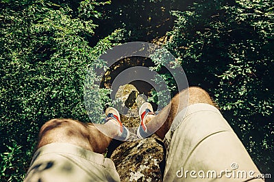 Traveler Man Sitting On Top Of Rock Over The Summer Forest, Point Of View Shot Stock Photo