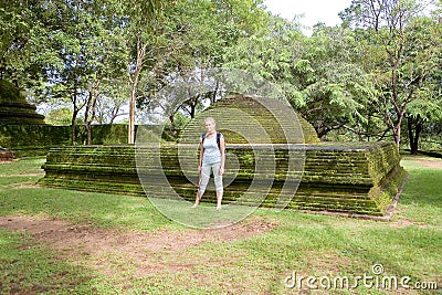 A traveler poses next to a large dome of an old building in Polonnaruwa Stock Photo