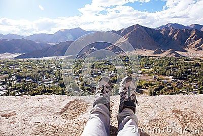 Traveler`s boots relaxing and resting his feet on high mountain trekking and ancient town scene and adventure Stock Photo