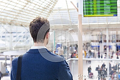 Traveler sending text message on smartphone in train station Stock Photo