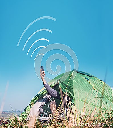Traveler sits in touristic camping tent and tries to catch cellular network. Cell web coverage and roaming concept image. Stock Photo