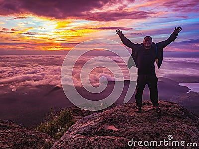 Traveler stand on Rocky cilff with sunsire sky and beautiful cloud sea on `Pa na rai` Khao Luang mountian Stock Photo