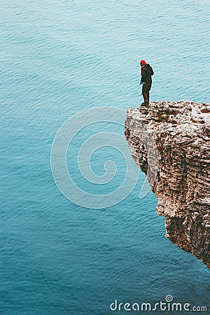 Traveler standing on cliff edge above sea alone Travel Lifestyle concept adventure Stock Photo