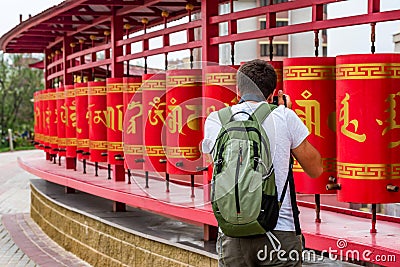 Traveler takes photo of red buddhist prayer wheels Editorial Stock Photo