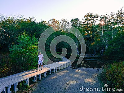 A traveler walking on the wooden pathway. Surrounded by nature. Senjogahara, Nikko, Japan. Stock Photo