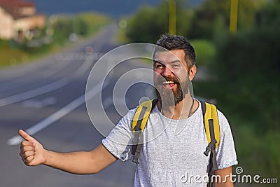 Traveling by autostop, having summer trip. Autostop travel. Man with strict face and beard travelling by hitchhiking Stock Photo