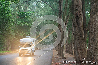 Traveling by campervan or motorhome on pine road. Stock Photo