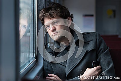 Traveling by train. Sad man traveling by train, looking through the window and thinking about unrequited love squeezing Stock Photo