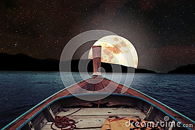 Traveling on wooden boat at night with full moon and stars on sky. romantic and scenic panorama with full moon on sea at night Stock Photo