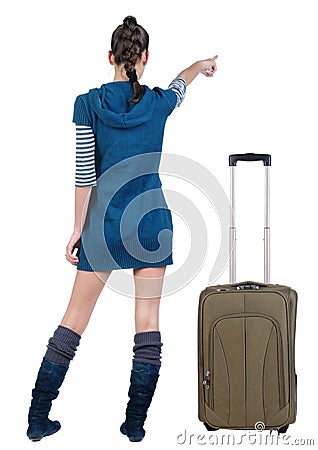 Traveling young woman in dress with suitcas pointing at wall Stock Photo