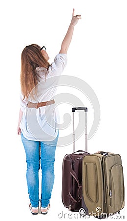 Traveling young woman with suitcas points at wall. Stock Photo