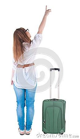 Traveling young woman with suitcas points at wall. Stock Photo