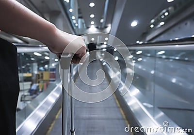 Traveller female holding suitcase on escalator at airport or transit flight with luggage on holiday traveling. Stock Photo